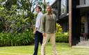 Two men walking in a garden with a modern house in the background